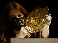 A member of staff poses with gold plate 'Visage de faune', by Spanish artist Pablo Picasso, estimated at GBP250,000-350,000, during a press...