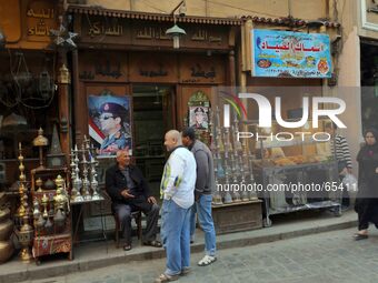 Shop owners talk outside empty shop with a poster showing support for potential presidentail candiate Gen. Sisi in the window on Al Moe'z St...