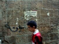 Young Egyptian man walks by a wall with a defaced poster for ousted former President Mohammed Morsi on Al Moe'z Street near Al Hussein Mosqu...