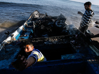 A Palestinian fishermen inspect their destroyed fishing boat hauled up onto the shore, close to the southern Gaza Strip town of Rafah, on th...