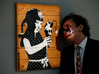 A member of staff poses with 'Girl With Ice Cream on Palette', by British artist Banksy, estimated at GBP300,000-500,000, during a press pre...