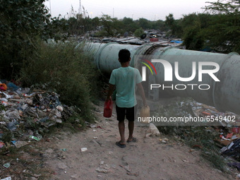 A man arrives to fill plastic containers with water coming out of a broken drinking water pipeline at a slum area on World Water Day in New...