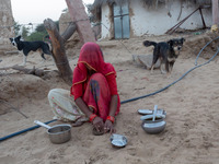 With less rainfall and water at scarce in the arid region of Thar desert, an Indian woman cleaning dishes with sand at Godu village, around...