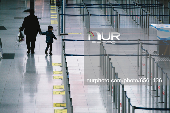 a kid is seen with his father walks in front of a empty check in counter at Duessedorf airport, Germany on March 26, 2021 as airlines adds m...