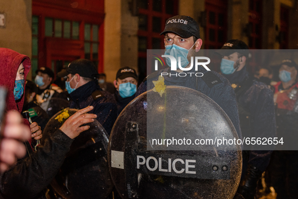 Protester displays daffodils on the officers' shields. Protesters gather in Bristol, UK  for the third time in a week on 26th March, 2021 to...