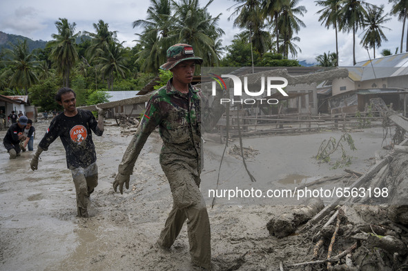 Soldiers and volunteers clean up the remaining mud that hit a house in Beka Village, Marawola District, Sigi Regency, Central Sulawesi Provi...