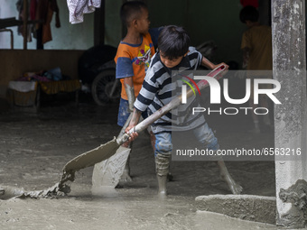 Children clean up the remaining mud that hit their house in Beka Village, Marawola District, Sigi Regency, Central Sulawesi Province, Indone...