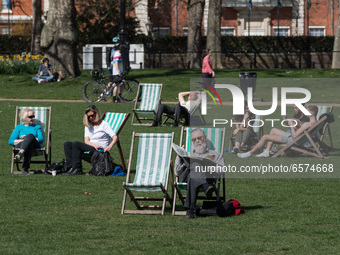 LONDON, UNITED KINGDOM - MARCH 30, 2021: People relax on deck chairs during exceptionally warm and sunny weather in St James's Park, making...