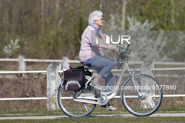 An old woman as seen cycling her bike. Sunny weather days with high temperatures, around 25 degrees centigrade during the spring season, lea...