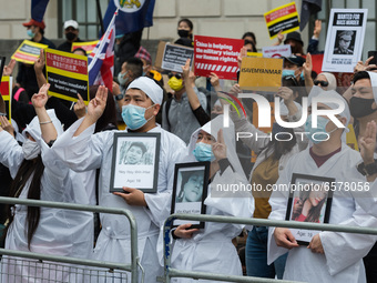 LONDON, UNITED KINGDOM - MARCH 31, 2021: Protesters wearing traditional white Chinese funeral attire give  a three-finger salute as they dem...