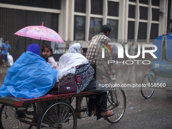 DHAKA, BANGLADESH  27th June : A family in a van covered with polythene and umbrella during rain  in Dhaka on 27th June 2015.Heavy raining i...