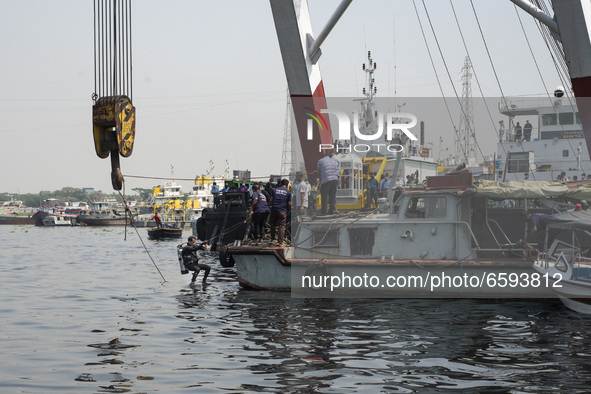 A member of rescue team jumps from a boat to go under water while trying to recover a capsized boat in Shitalakshya River, in Narayanganj on...