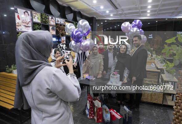 An Iranian family living in the holy city of Qom, 145Km (90 miles) south of Tehran, take photographs during a birthday party at a fast-food...
