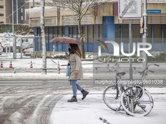 A young woman as seen walking on the snow in Eindhoven city center, holding an umbrella next to some bicycles. The third day of the unusual...