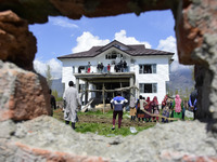 Kashmiri people assess the damaged residential house where the militants were believed to be trapped during cordon in Gulab Bagh area of Sri...