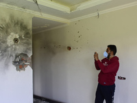 A Kashmiri man clicls pictures inside a damaged residential house where the militants were believed to be trapped during cordon in Gulab Bag...