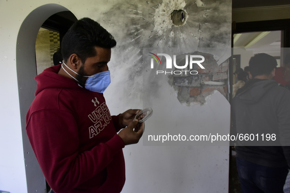 Kashmiri people assess the damaged residential house where the militants were believed to be trapped during cordon in Gulab Bagh area of Sri...