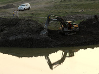 An excavator removes soil from a water body near the Yamuna river for a beautification scheme, in New Delhi, India on April 7, 2021. The IMF...