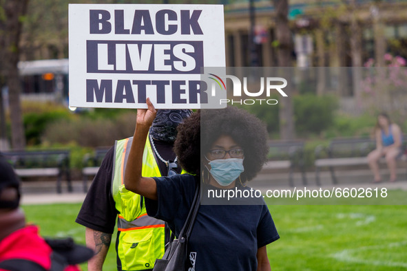A woman holds a Black Lives Matter flag as people gather at Washington Park in memorial and then march to where Timothy Thomas died 20 years...