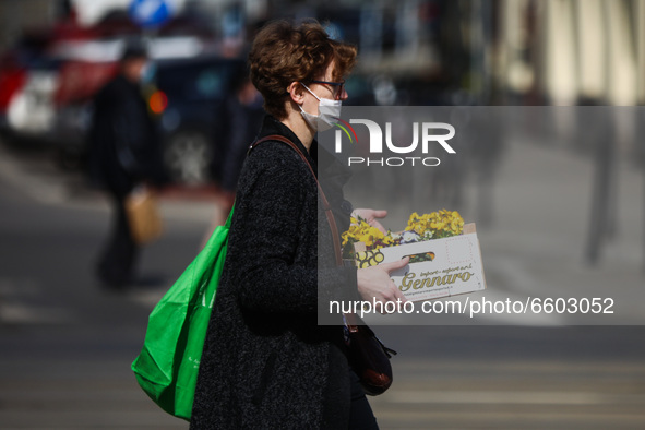 A woman carries spring flowers during coronavirus pandemic in Krakow, Poland on April 1st, 2021. 