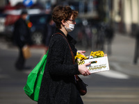 A woman carries spring flowers during coronavirus pandemic in Krakow, Poland on April 1st, 2021. (