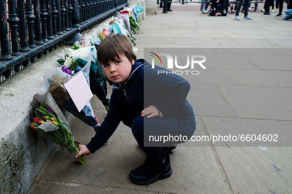 Boy lays down a bouquet of flowers outside Buckingham Palace after it was announced that Britain's Prince Philip, husband of Queen Elizabeth...