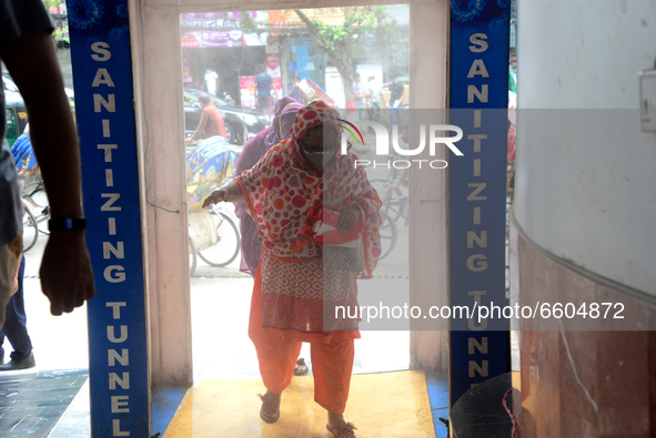 Shoppers going through a disinfection chamber of a Shopping Malls to buy clothes at a shop following a limited opening of shopping malls dur...