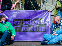 Two XR activists are talking in front of the XR banner, during the  massive disruptive action carried out by Extinction Rebellion, on April...