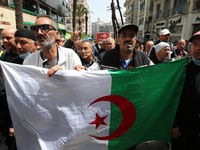 Algerian protesters raise a national flag as they march demanding political change in the capital Algiers on April 9, 2021. (
