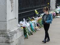 LONDON, UNITED KINGDOM - APRIL 10, 2021: A young girl lays flowers outside Buckingham Palace a day after the death of Prince Philip, on 10 A...