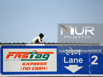 A worker gives the final touches to the roof of a toll plaza with FASTag facility, at KMP Expressway in Ghaziabad on the outskirts of New De...