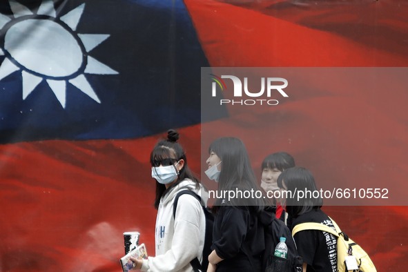 Taiwanese people wearing a face walk mask pass a Taiwan flag banner, amid heated tensions with Beijing, in Taipei, Taiwan, 11 April 2021. Wi...