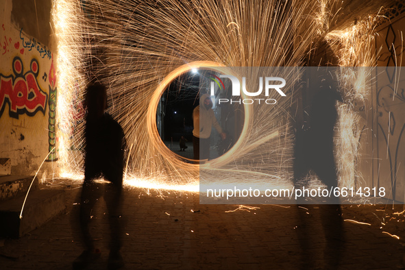 A Palestinian youth swings a homemade fireworks sparkler, as people celebrate on the night ahead of the Muslim holy fasting month of Ramadan...