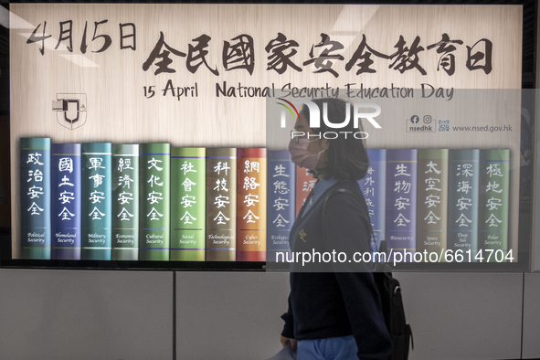 People walk pass a poster for the National Security Education Day, in Hong Kong, Monday, April 12, 2021. Hong Kong will host a National Secu...