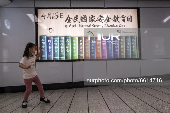 A girl stand next to a poster for the National Security Education Day, in Hong Kong, Monday, April 12, 2021. Hong Kong will host a National...