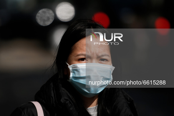 A woman wearing a face mask waits at a bus stop on Oxford Street in London, England, on April 12, 2021. Coronavirus lockdown measures were f...