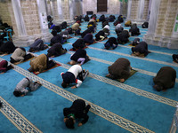 Palestinian Muslims pray spaced apart as they practice social distancing to curb the spread of the new coronavirus during an evening prayer...