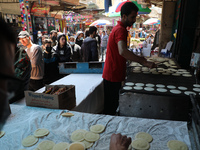Palestinians wait past a Palestinian pastry chef preparing 