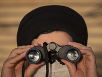 An Iranian cleric looks at the sky through the binoculars during a ceremony for observation of the new moon of Muslim’s holy month of Ramada...