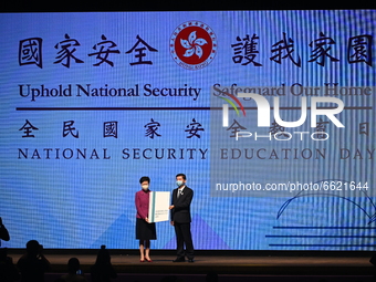 (Left) Hong Kong Chief Executive Carrie Lam accepts large booklet from The Director of the Liaison Office of the Central People's Government...