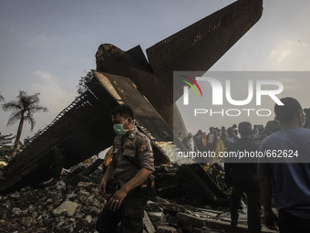 An Indonesian police walking on debris of air force-owned aircraft that crashed in Medan, North Sumatra, Indonesia on June 30, 2015. The Her...