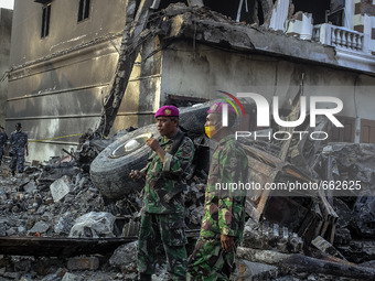 An Indonesian military standing on debris of air force-owned aircraft that crashed in Medan, North Sumatra, Indonesia on June 30, 2015. The...