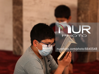 Young Palestinian boys wearing face masks due to the coronavirus pandemic, read the Koran during the Muslim holy month of Ramadan, in Khan Y...