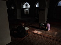 Syrian Muslims read the Qur'an in the old mosque in the town of Maarat Misreen in the northern countryside of Idlib during the blessed month...
