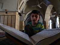Syrian Muslims read the Qur'an in the old mosque in the town of Maarat Misreen in the northern countryside of Idlib during the blessed month...
