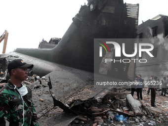 Indonesian military personnel standing beside the ruins of Indonesian aircraft C-130 Hercules day after the crash in Medan, North Sumatra, I...
