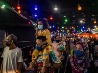 A girl wears a face mask while sitting on her father's shoulders at a Ramadan bazaar during the holy month of Ramadan in Kuala Lumpur, on Ap...