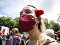 A woman wearing a face mask holds a red carnation in her hair during a demonstration to commemorate the anniversary of Portugal's Red Carnat...