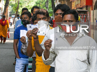 People wearing mask shows their voter id card as they queued in front  of a polling station , during 7th phase of West Bengal assembly elect...