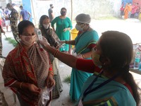 Health worker checks the temperature  at a polling station during the 7th   phase of  West Bengal's  state legislative assembly elections  i...